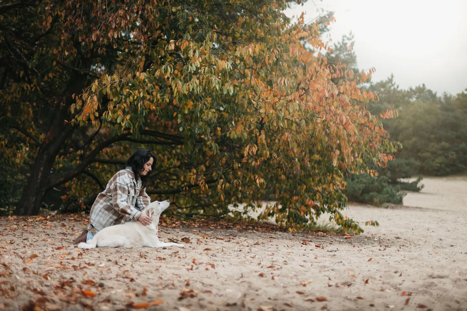 Simone zit met haar hond onder een herfstboom